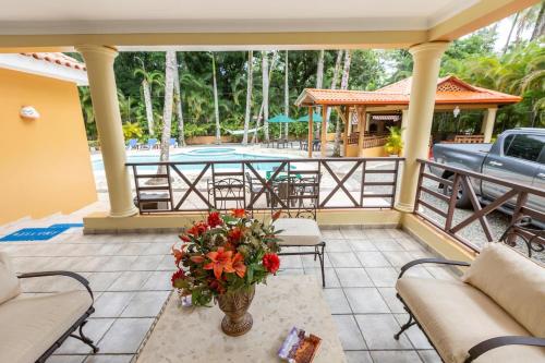 a patio with a table with a vase of flowers at Huttub Dailycleaning Gacebo Bbq River in Bonao