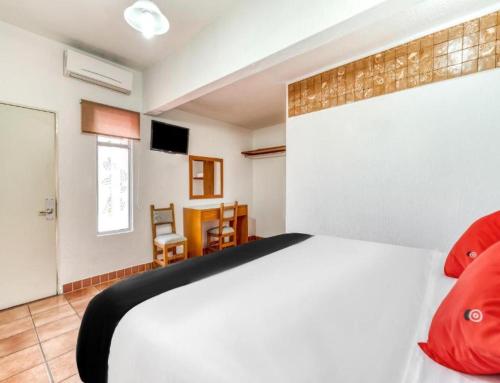 a bedroom with a large white bed with red pillows at Hotel Arana Tonalá in Guadalajara