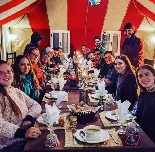 a group of people sitting at a long table at Merzouga Desert Experience Camp-Erg Chebbi Sunset & Camel Ride in Merzouga