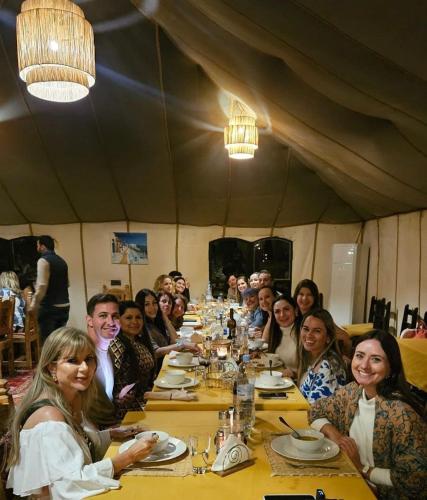 a group of people sitting at a long table at Merzouga Desert Experience Camp-Erg Chebbi Sunset & Camel Ride in Merzouga