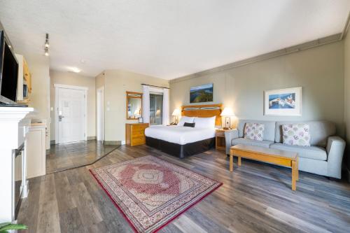 a bedroom with a bed and a couch at Sidney Waterfront Inn & Suites in Sidney