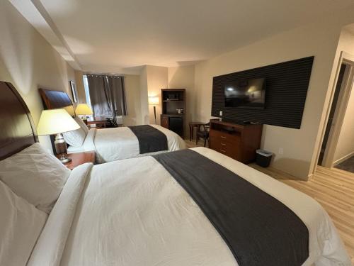 a hotel room with two beds and a flat screen tv at Auberge Le Chardo Inn 