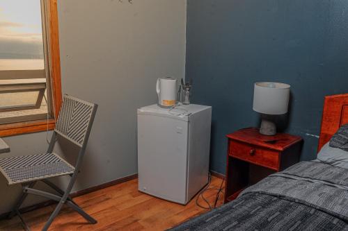 a room with a refrigerator and a chair and a bed at Cabañas Bordemar Habitaciones para 2 y 3, Cabañas para 4 y 5 huéspedes in Tomé