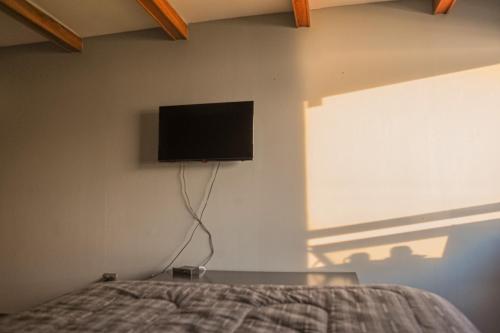 a bedroom with a bed with a tv on the wall at Cabañas Bordemar Habitaciones para 2 y 3, Cabañas para 4 y 5 huéspedes in Tomé