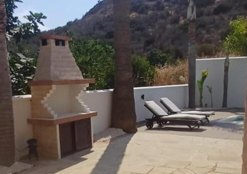 a patio with two chairs and a fireplace at Eros Villa-Private Luxury Estate in Pissouri
