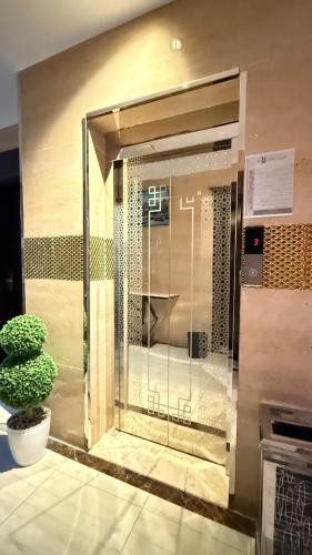 a glass door in a building with a potted plant at نصف القمر للشقق المخدومة in Ḩaql