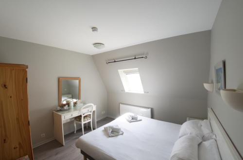 a white bedroom with a bed and a desk at Château Baffy in Colombiers-sur-Seulles