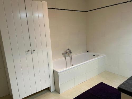 a white bathroom with a tub and a sink at Rotessa in Blankenberge