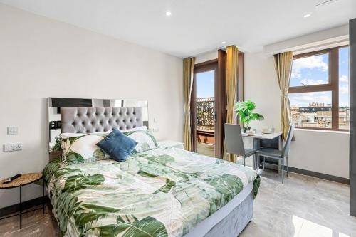 a bedroom with a large bed with a desk and a window at Modern Studio with Balcony Godino Hotel Ilford in Ilford