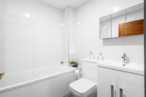 a white bathroom with a tub and a toilet and a sink at Modern Studio with Balcony Godino Hotel Ilford in Ilford