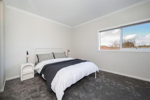 a white bedroom with a bed and a window at Solara House with Heated Pool and Cinema Room in Safety Beach