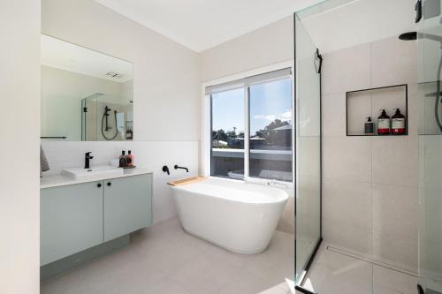a white bathroom with a tub and a glass shower at Solara House with Heated Pool and Cinema Room in Safety Beach