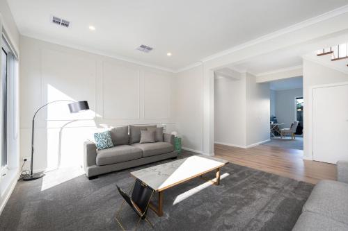 a living room with a couch and a table at Solara House with Heated Pool and Cinema Room in Safety Beach