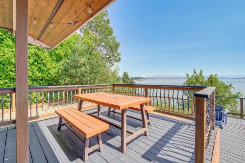 a wooden table and bench on a deck with the water at Mtn-View Camano Island Retreat Overlooking Beach in Camano