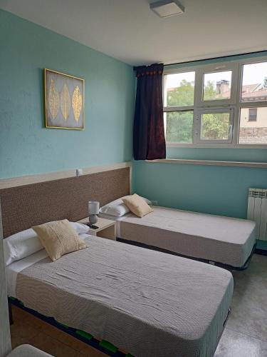 two beds in a room with two windows at Hostal Camino micológico in Navaleno