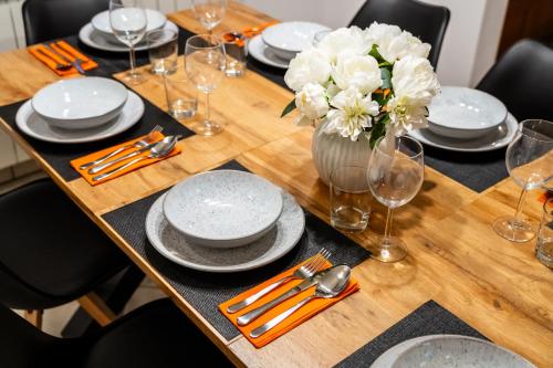 a wooden table with plates and a vase of flowers at Spacious Apartment Senozece - with terrace & grill in Senožeče