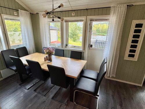 a dining room with a wooden table and black chairs at Riverfront house with 98 inch TV, ps5 & activities in Narvik