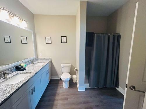 a bathroom with a toilet and two sinks and a shower at Spacious Wyoming MI Getaway- Minutes to GR in Wyoming