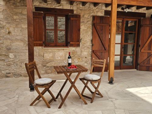 a table with a bottle of wine and two chairs at Katerinas Sweet Place studio 1 in Tsadha