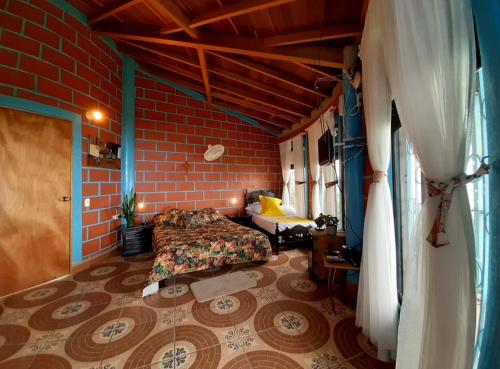 une chambre avec un lit et un mur de briques dans l'établissement Finca turística Villa Carolina, à Sabaletas