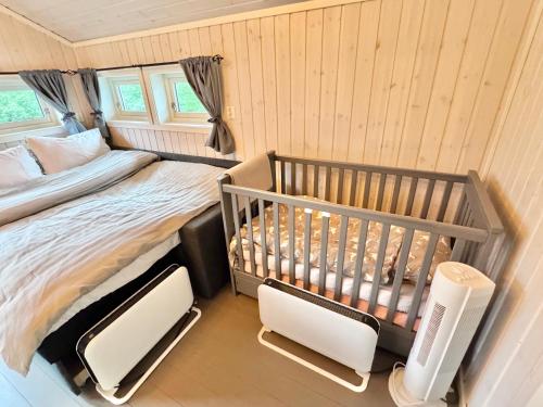 a bedroom with a crib and two chairs in it at Riverfront house with 98 inch TV, ps5 & activities in Narvik
