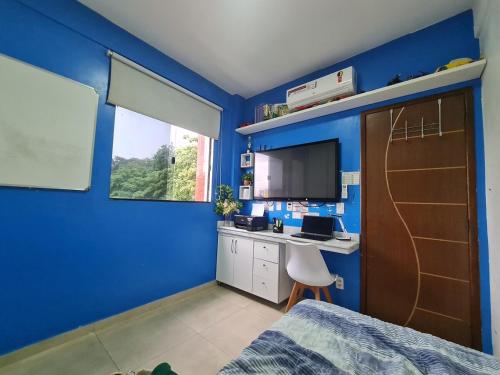 a blue room with a bedroom with a desk and a bed at Apto na COP 30 in Belém