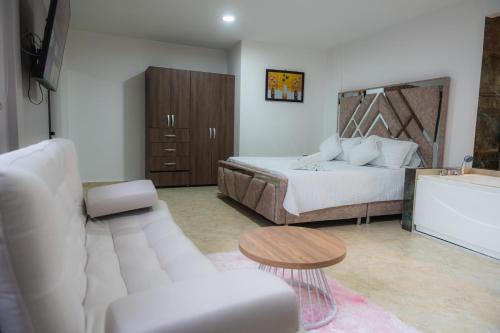 a bedroom with a bed and a couch and a table at Hotel Boutique Campestre in Florencia