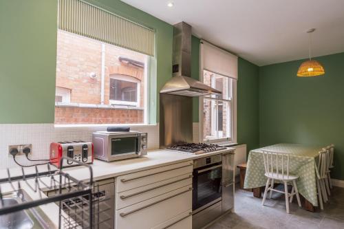a kitchen with green walls and a counter with a microwave at College Avenue Stay in Leicester