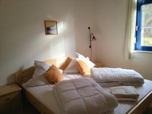 une chambre avec un lit avec des draps blancs et des oreillers dans l'établissement Fewo Wellenblick Trassenheide Usedom, à Trassenheide