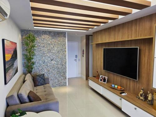 Una sala de estar con un sofá y un televisor de pantalla plana. en Apartamento Barra da Tijuca Frente Mar, en Río de Janeiro