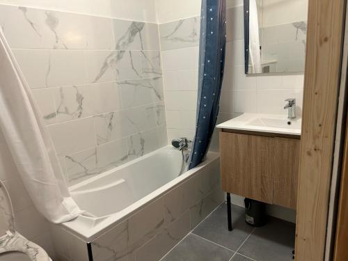 a bathroom with a white tub and a sink at maison entiere clairac 3 chambres in Clairac