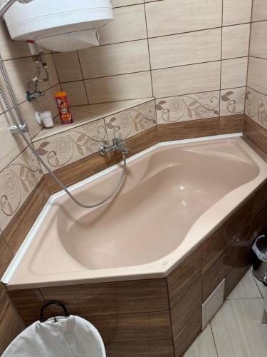 a bath tub with a hose in a bathroom at La Casa De Nido-Tágas családias apartman 6 főig, kerttel in Veszprémfajsz