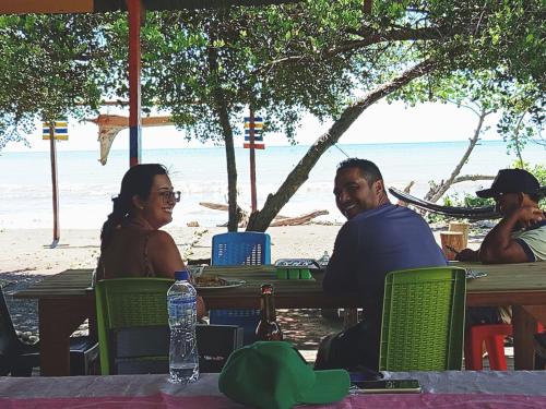 a man and woman sitting at a table on the beach at Cabaña y restaurante vikana in Nuquí