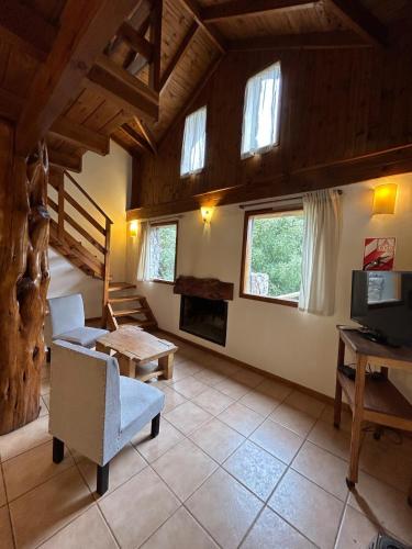 a living room with a couch and a table and windows at Hermosa cabaña a orillas del rio in Junín de los Andes