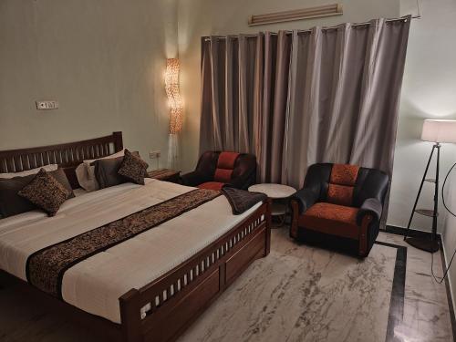 Un dormitorio con una cama grande y dos sillas. en Aathira urbanite, en Chennai