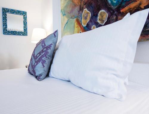 a white bed with two pillows and a painting at Colombe Hotel Boutique in Xalapa