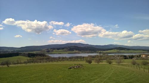 a green field with a view of a lake and mountains at Penzion Lipno Jantar in Horní Planá