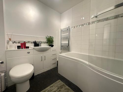 a white bathroom with a toilet and a sink at Exquisite 2Bed Near Transport Link & Bluewater Mall in Stonewood