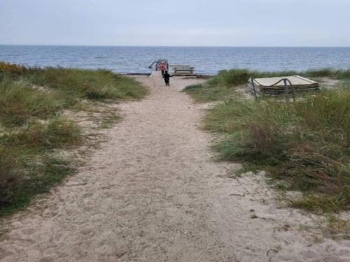 a person walking down a path on a beach with an umbrella at 8 person holiday home in Dannemare-By Traum in Dannemare