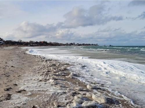 a beach with snow on the sand and the ocean at 5 person holiday home in Føllenslev-By Traum in Føllenslev