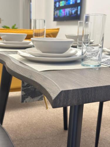a table with plates and glasses on top of it at Exquisite 2Bed Near Transport Link & Bluewater Mall in Stonewood