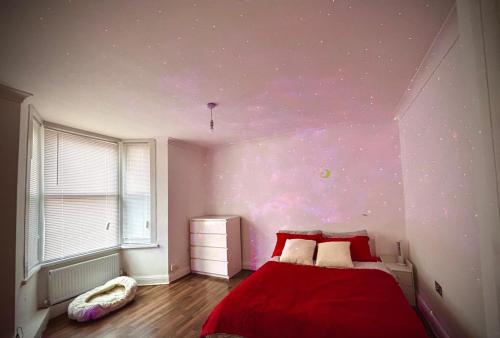 a bedroom with a red bed and a purple wall at Stratford Accommodation in London