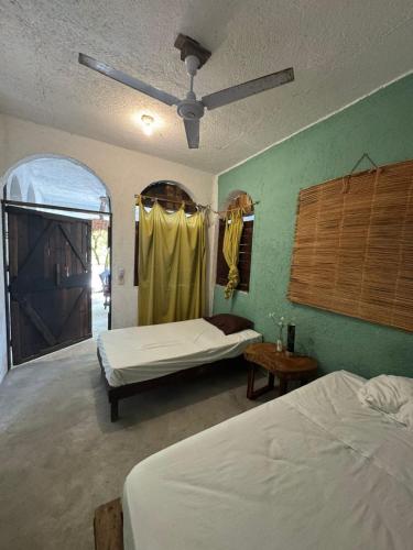 a bedroom with two beds and a ceiling fan at El árbol de la vida Hostel - Private Rooms Near Bacalar Lagoon in Bacalar