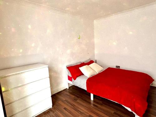 a small bedroom with a red bed and a dresser at Stratford Accommodation in London