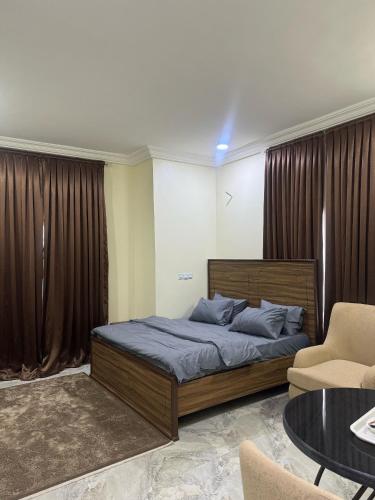 a bedroom with a bed and a couch and a table at ILHAM SUITEs in Abuja