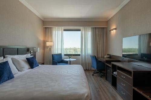 a hotel room with a bed and a desk and a television at Marriott Hotel Buenos Aires Ezeiza Airport in Ezeiza