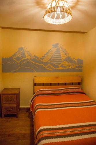 a bedroom with a bed with a painting on the wall at Hostel Casa De Yagil in San Cristóbal de Las Casas