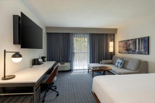 a hotel room with a bed and a desk at Courtyard by Marriott North Charleston Airport Coliseum in Charleston