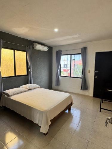 a bedroom with a large bed and two windows at Casa Amelia Victoria in Mérida