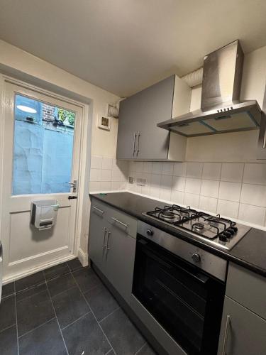 a kitchen with a stove top oven next to a window at Stratford Accommodation in London